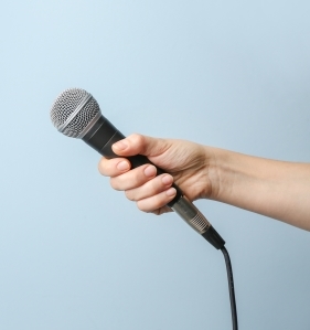 Female hand with microphone on color background